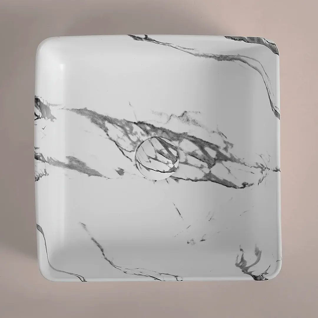vasque à poser carrée en céramique avec finition effet marbre calacatta, dotée d’une bonde assortie.